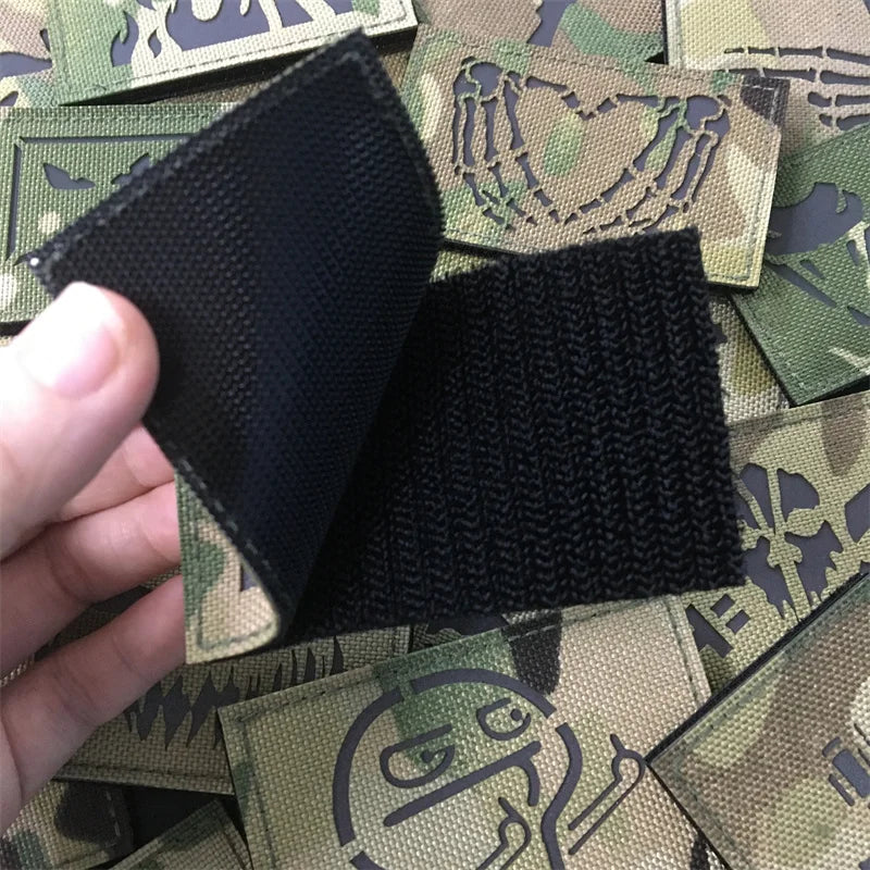 patch showing its Velcro backing   held over a collection of green tactical patches with designs