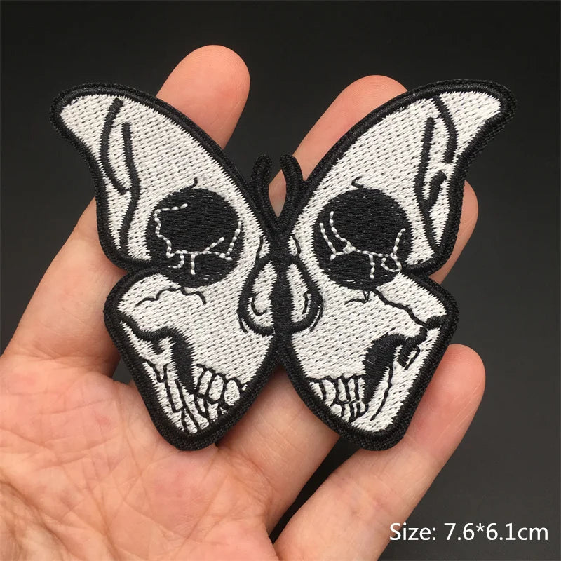Butterfly-shaped skull patch held in a hand with a dark background