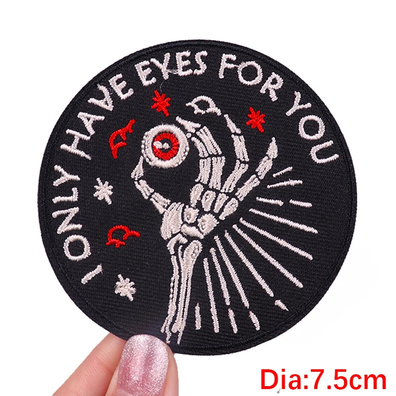 Circular patch with skeleton hand and text 'Only have eyes for you' held by a hand.