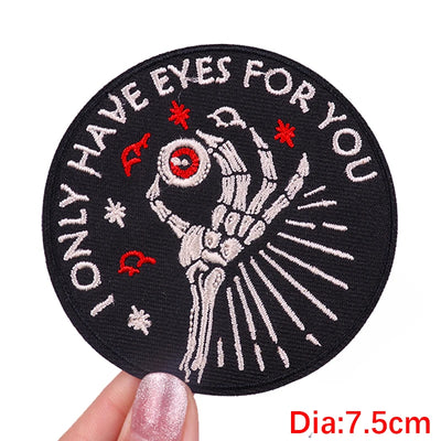 Circular patch with skeleton hand and text 'Only have eyes for you' held by a hand.