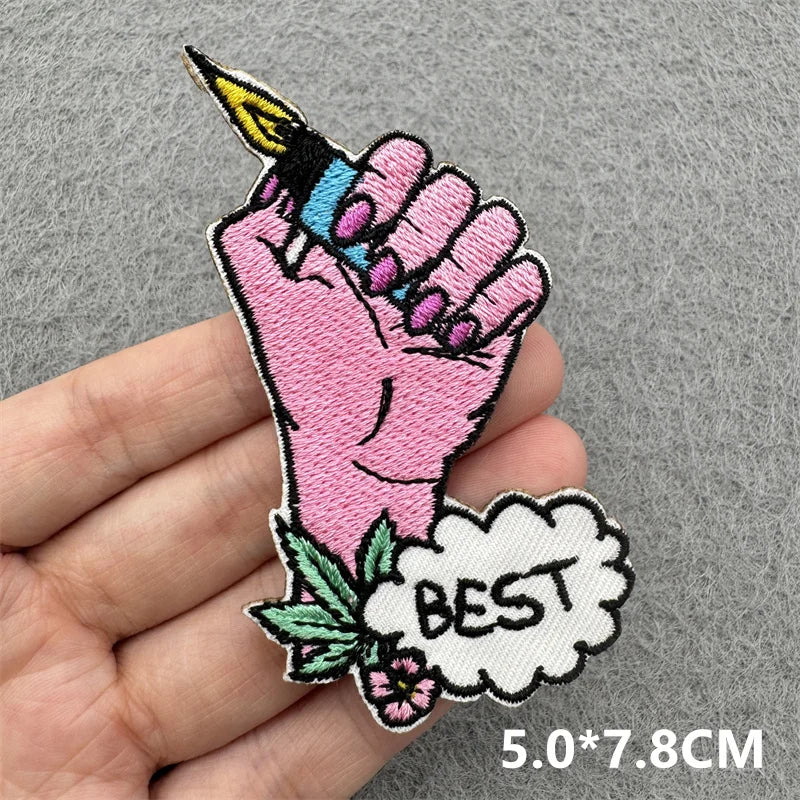 Embroidered patch of a pink hand holding a tattoo with &