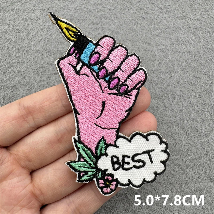 Embroidered patch of a pink hand holding a tattoo with &