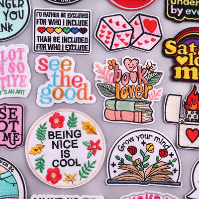 Collection of colorful patches with motivational and decorative text and designs on a gray background.
