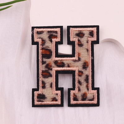 Leopard print letter 'H' patch on a light fabric background