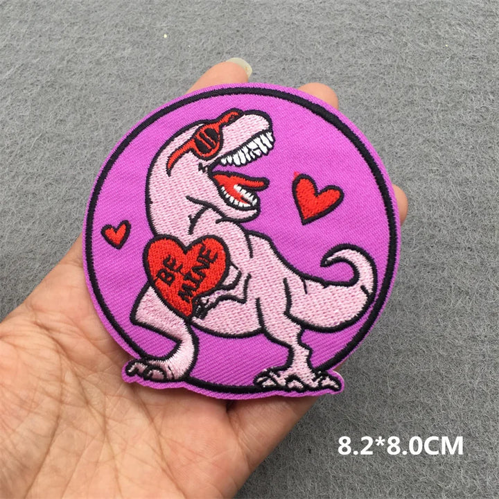 Embroidered patch with a dinosaur holding a heart and &