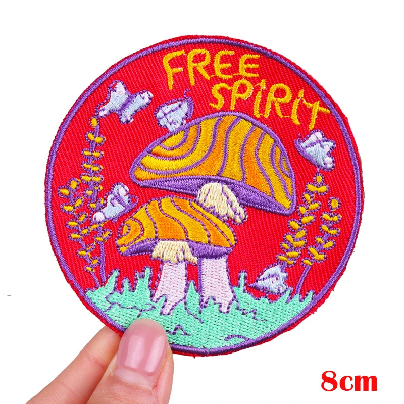 Embroidered patch with mushrooms and 'Free Spirit' text held by a hand on a white background