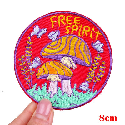 Embroidered patch with mushrooms and 'Free Spirit' text held by a hand on a white background