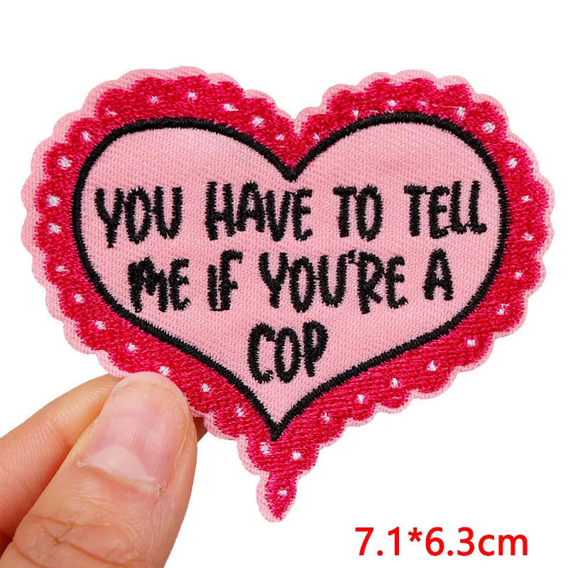 Heart-shaped patch with text held by a hand on a white background