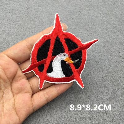 Embroidered patch with a red and black design held in a hand on a gray background