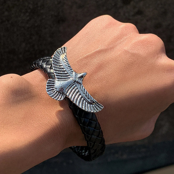 Bracelet with an eagle emblem on a wrist against a dark background