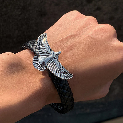 Bracelet with an eagle emblem on a wrist against a dark background