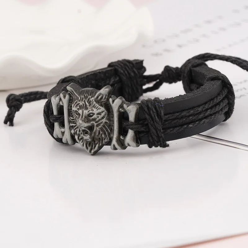 Black braided bracelet with a wolf head charm on a white background