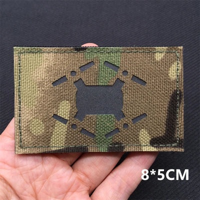 Camouflage patch with a mine black symbol held by a hand on a dark background