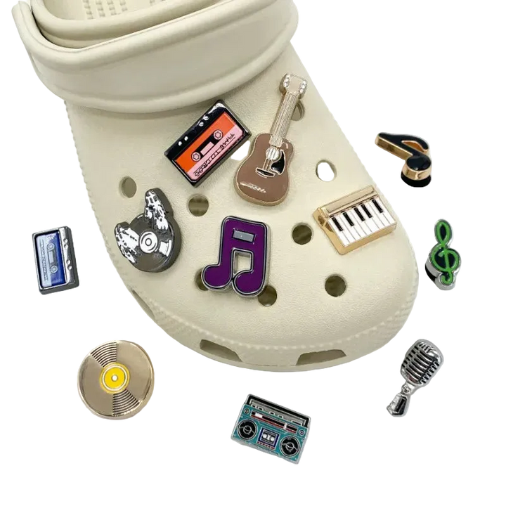 Beige croc shoe with various music-themed charms on a white background