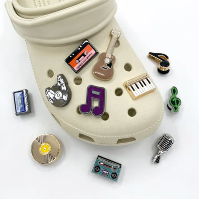 Beige croc shoe with music-themed charms on a white background