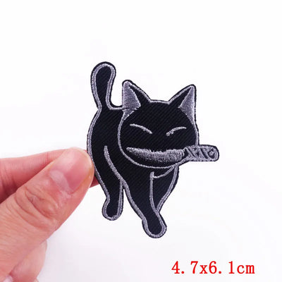Embroidered patch of a black cat with a white patch on a white background