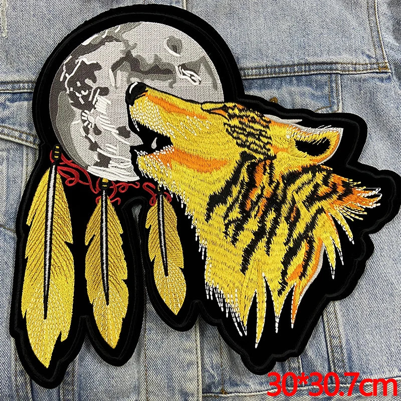Embroidered patch of a wolf howling with feathers on a denim background