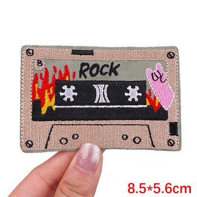 Patch of a cassette tape with 'Rock' text held by a hand, on a white background