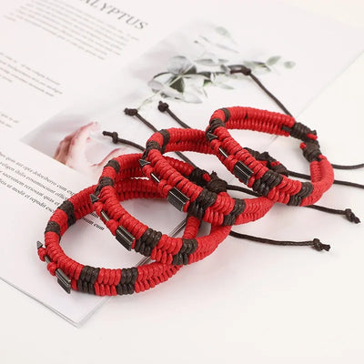 Red and black braided bracelets on a magazine page