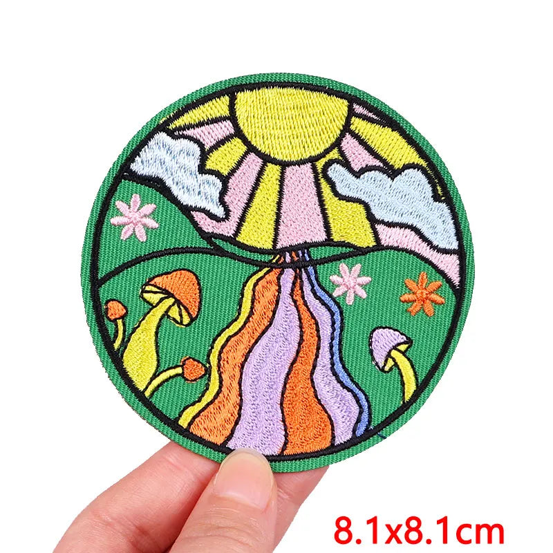 Circular embroidered patch with nature design held by a hand, size 8.1x8.1cm.