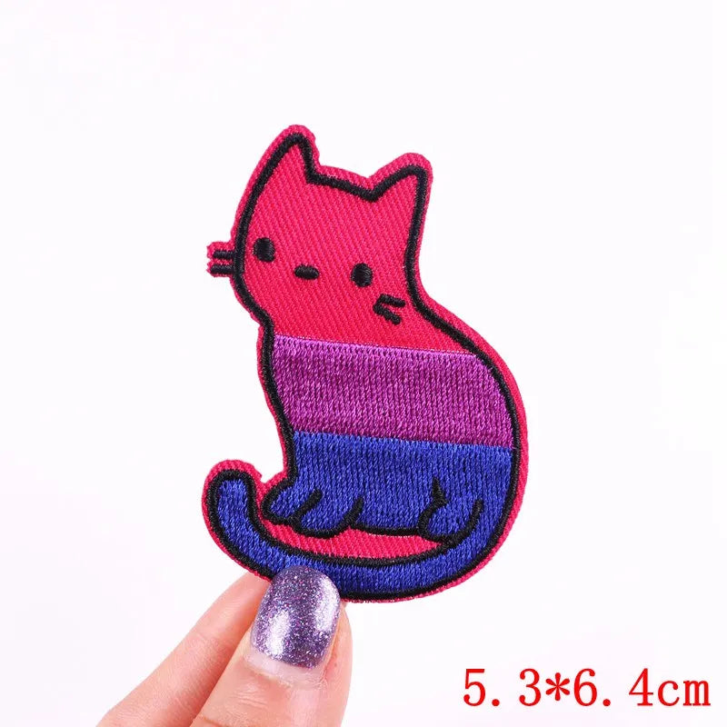 Colorful cat-shaped patch held by a hand with a white background