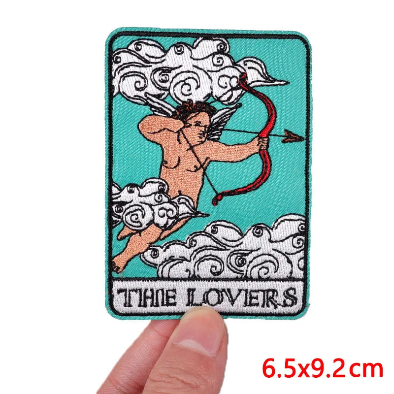 Patch of Cupid and Psyche with 'The Lovers' text, held by a hand against a white background.