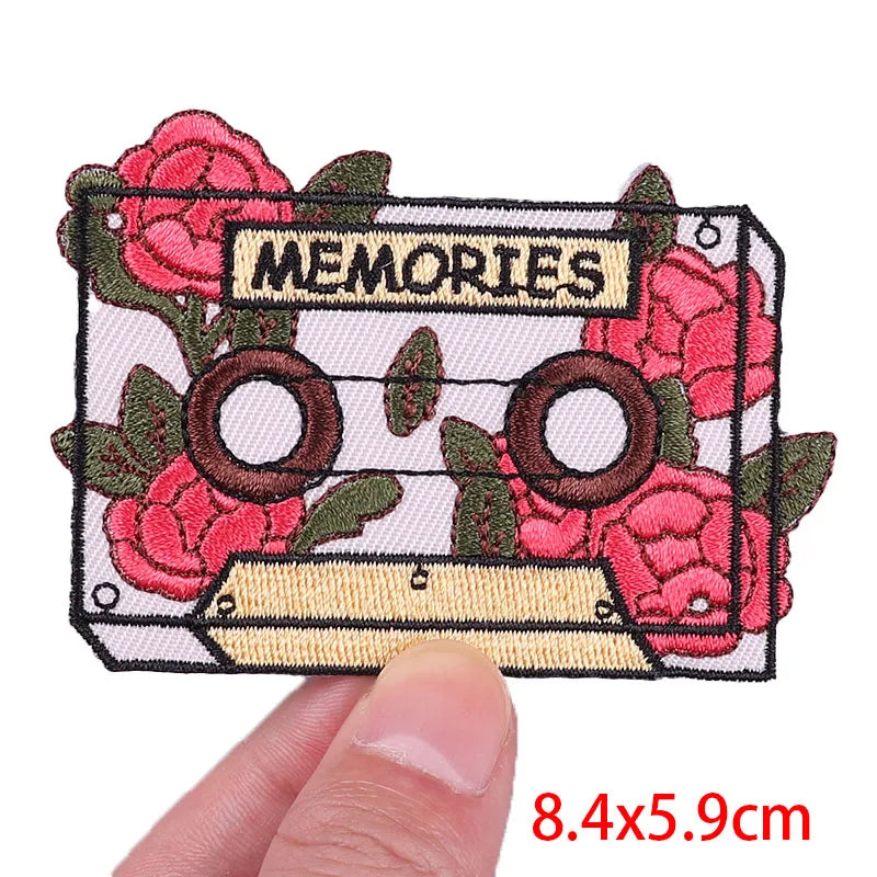 Embroidered patch with cassette tape and roses design, labeled 'MEMORIES', held by a hand.