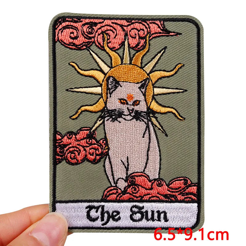 Embroidered patch with a cat and sun design, labeled 'The Sun', held by a hand.