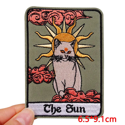 Embroidered patch with a cat and sun design, labeled 'The Sun', held by a hand.