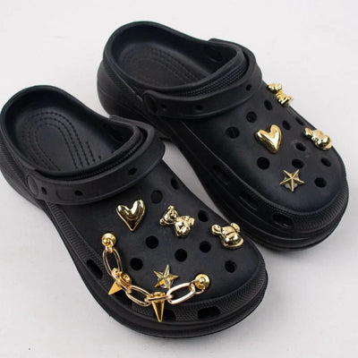 Black clogs with gold charms on a white background