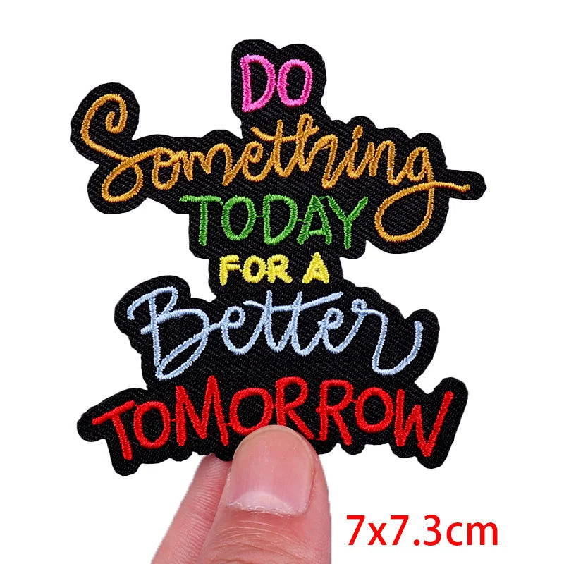 Motivational patch with colorful text held by a finger on a white background