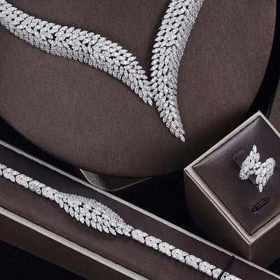 Silver jewelry set including necklace, bracelet, ring and earrings on a brown surface.