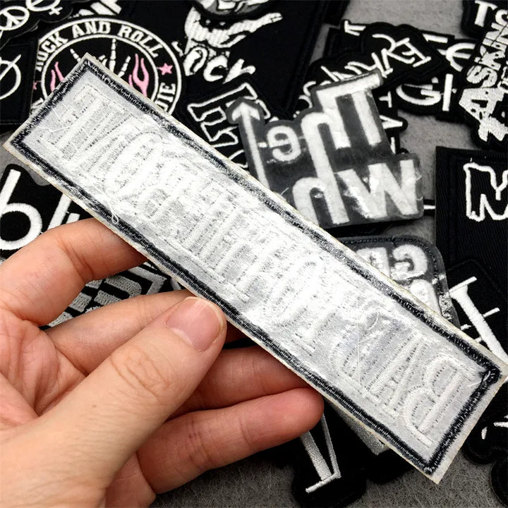 Hand holding a rectangular patch with text, surrounded by other similar patches.