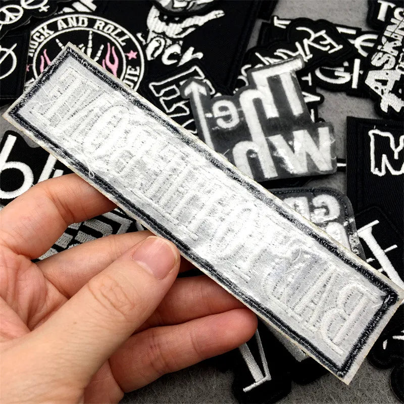 Hand holding a rectangular patch with text, surrounded by other similar patches.