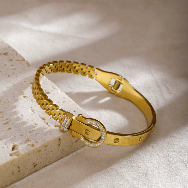Gold bracelet with diamond accents on a textured beige surface