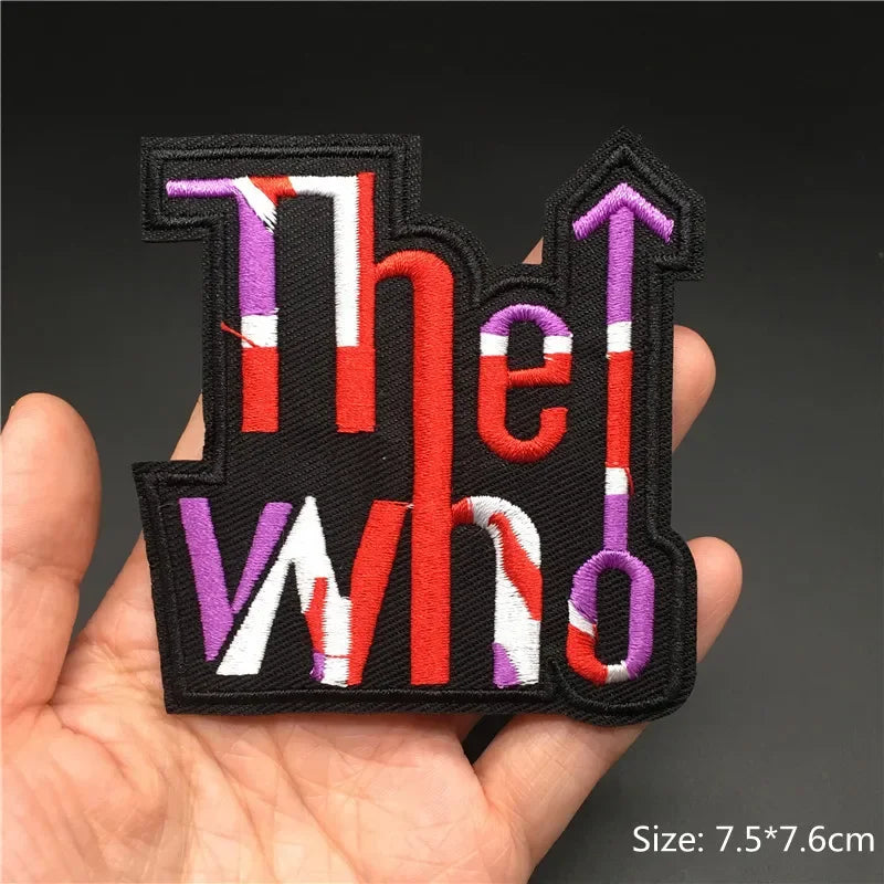 Hand holding a multicolor The Who embroidered iron-on patch 7.5x7.6cm on a dark background