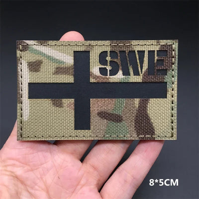 Sweden flag Camouflage patch held in a hand against a dark background
