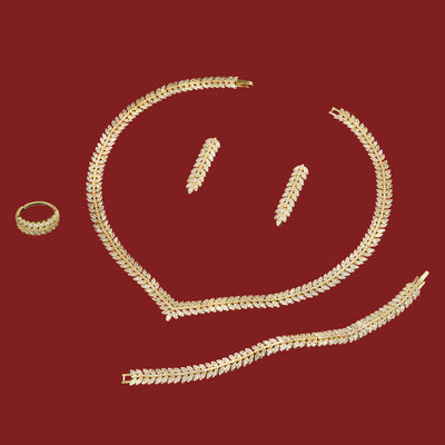 Gold jewelry set including necklace, bracelet, ring, and earrings on a red background