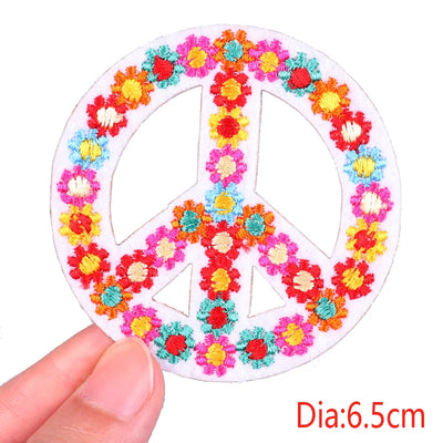 Peace symbol with floral design held by a hand, labeled 'Diameter: 6.5cm'.