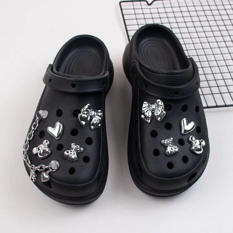Black clogs with silver decorative charms on a white background