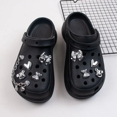 Black clogs with silver decorative charms on a white background