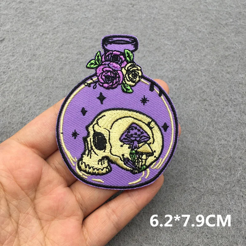 Skull and floral design patch held by a hand on a gray background