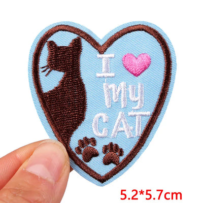 Heart-shaped patch with a cat silhouette and 'I love my cat' text held by a hand.