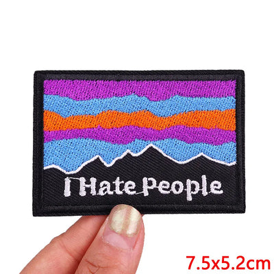Colorful patch with 'I Hate People' text held by a hand, on a white background