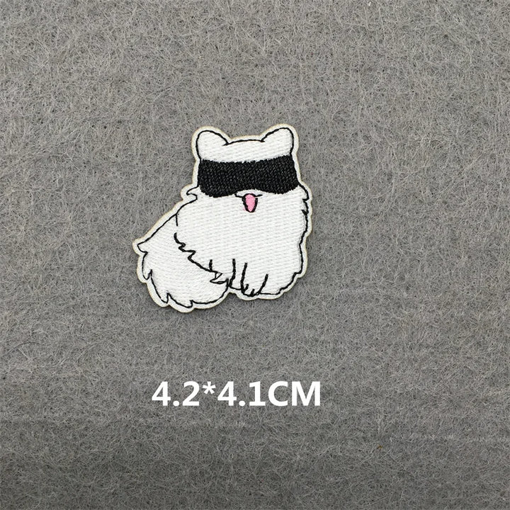 Embroidered patch of a cartoon cat with a blindfold on a gray background