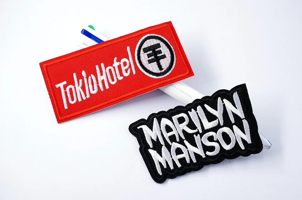 Two patches, one red with 'Tokio Hotel' text and another black with 'Marilyn Manson' text, on a white background.
