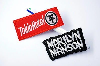 Two patches, one red with 'Tokio Hotel' text and another black with 'Marilyn Manson' text, on a white background.