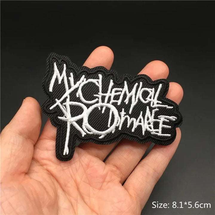 Hand holding a black and white My Chemical Romance embroidered iron-on patch 8.1x5.6cm on a dark background