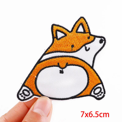 Fox-shaped patch held by a hand with dimensions 7x6.5cm on a white background