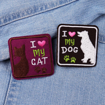 Two embroidered patches on a denim jacket, one with 'I love my cat' and the other with 'I love my dog'.